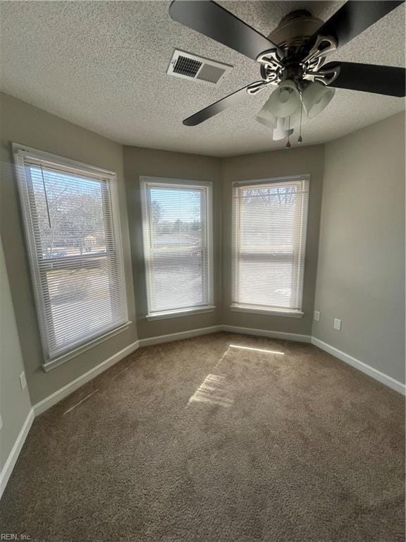 carpeted empty room with a healthy amount of sunlight, visible vents, and baseboards