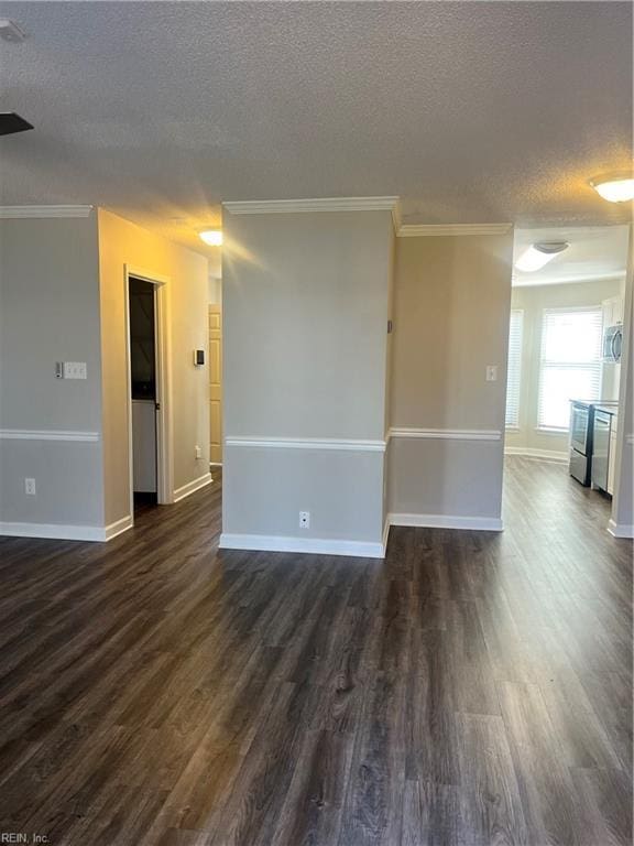 empty room with dark wood finished floors, a textured ceiling, baseboards, and ornamental molding