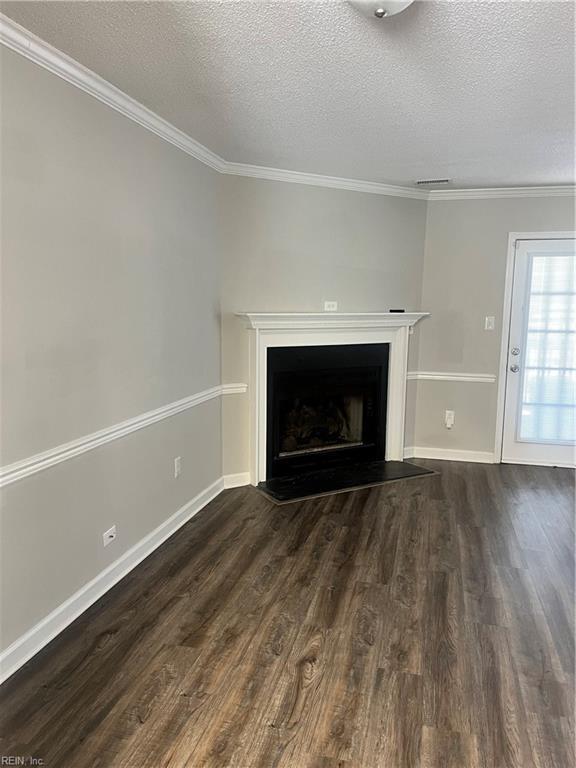 unfurnished living room with a fireplace with flush hearth, dark wood-style floors, and ornamental molding