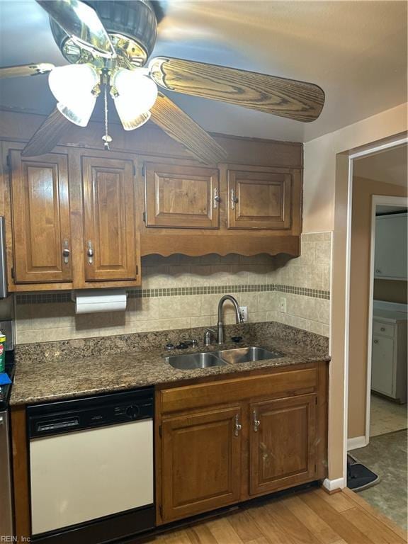 kitchen featuring tasteful backsplash, ceiling fan, light wood-style flooring, white dishwasher, and a sink