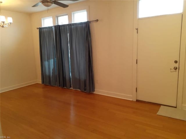 interior space featuring baseboards, light wood-style floors, and ceiling fan with notable chandelier