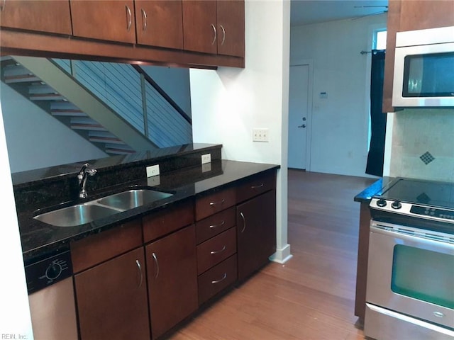 kitchen with a sink, stainless steel appliances, decorative backsplash, and light wood finished floors