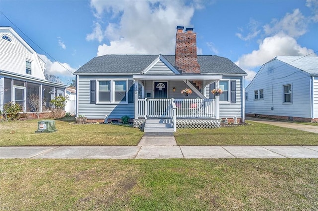 bungalow-style house with a front lawn, covered porch, roof with shingles, and a chimney