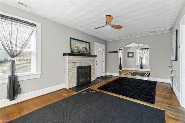 entrance foyer with a fireplace, visible vents, wood finished floors, and arched walkways