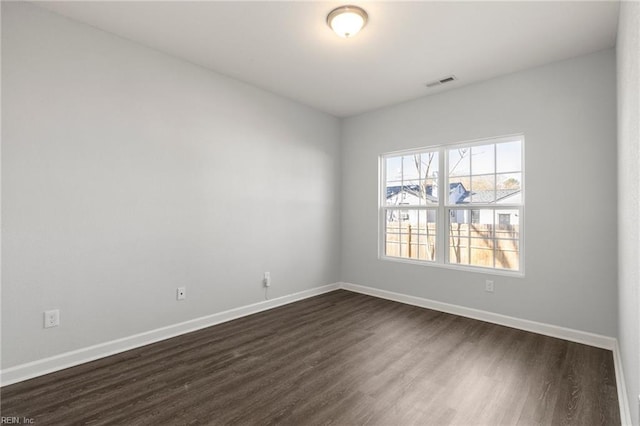 spare room with visible vents, baseboards, and dark wood-style flooring