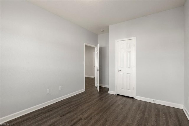 empty room with baseboards and dark wood-style flooring