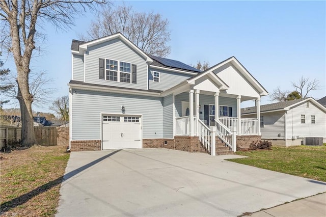 view of front of property with a front lawn, roof mounted solar panels, a porch, fence, and concrete driveway