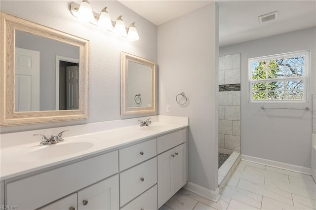 bathroom featuring visible vents, marble finish floor, a tile shower, and a sink