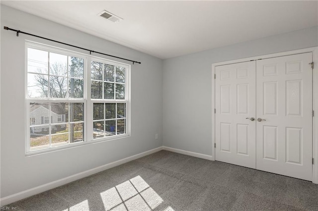 unfurnished bedroom featuring a closet, carpet flooring, multiple windows, and baseboards