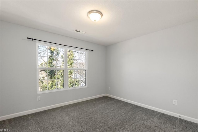 spare room with visible vents, baseboards, and dark carpet