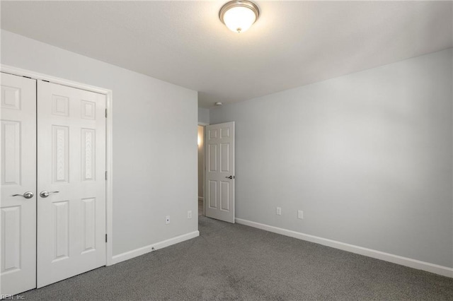 unfurnished bedroom with a closet, baseboards, and dark colored carpet