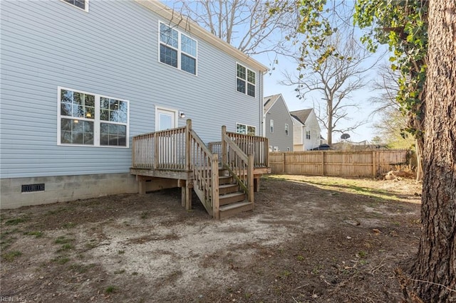 rear view of house featuring a deck, fence, and crawl space