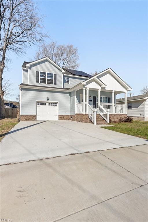 view of front of house with concrete driveway, a garage, covered porch, and roof mounted solar panels