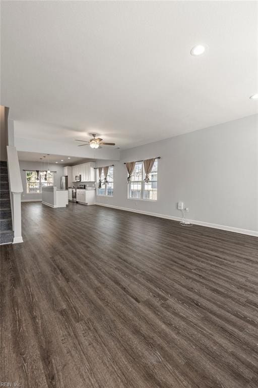 unfurnished living room featuring dark wood finished floors, stairs, and baseboards