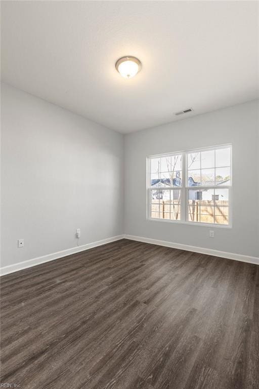 unfurnished room featuring visible vents, baseboards, and dark wood-style flooring