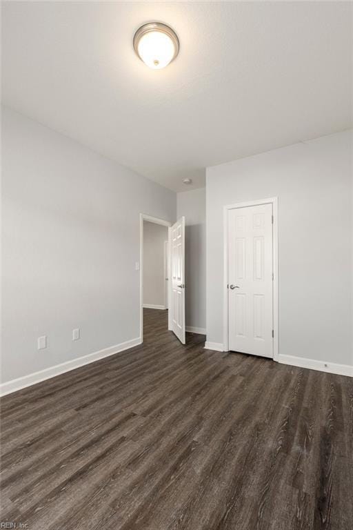 empty room with dark wood finished floors and baseboards