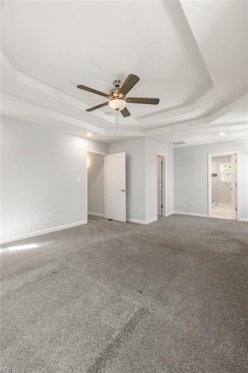 carpeted empty room featuring baseboards, a tray ceiling, and a ceiling fan