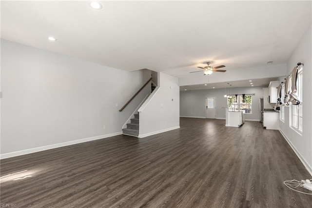 unfurnished living room with a ceiling fan, baseboards, dark wood finished floors, recessed lighting, and stairs