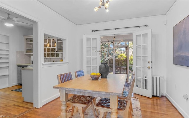 dining space with baseboards, radiator heating unit, ceiling fan, ornamental molding, and light wood-style floors