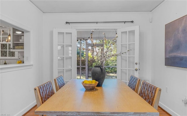 dining space featuring baseboards, wood finished floors, and crown molding