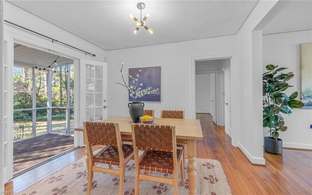 dining room featuring baseboards, a notable chandelier, and light wood-style flooring