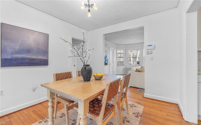 dining room featuring an inviting chandelier, baseboards, light wood finished floors, and ornamental molding