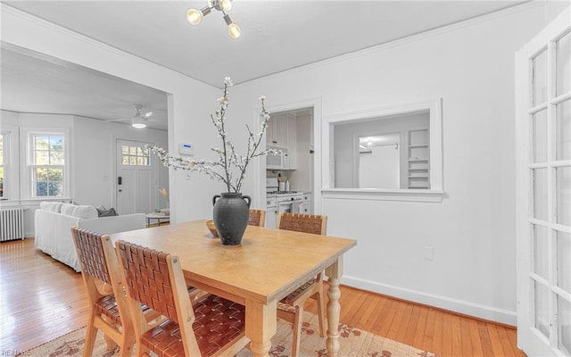 dining space featuring radiator, baseboards, ceiling fan, ornamental molding, and light wood-type flooring