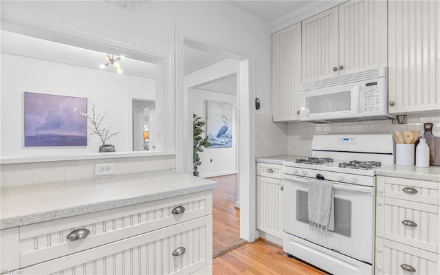 kitchen featuring light wood-type flooring, decorative backsplash, white appliances, and baseboards