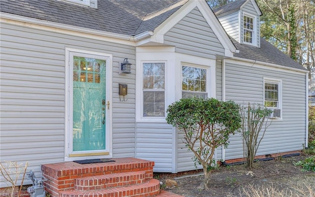 view of exterior entry with crawl space and roof with shingles