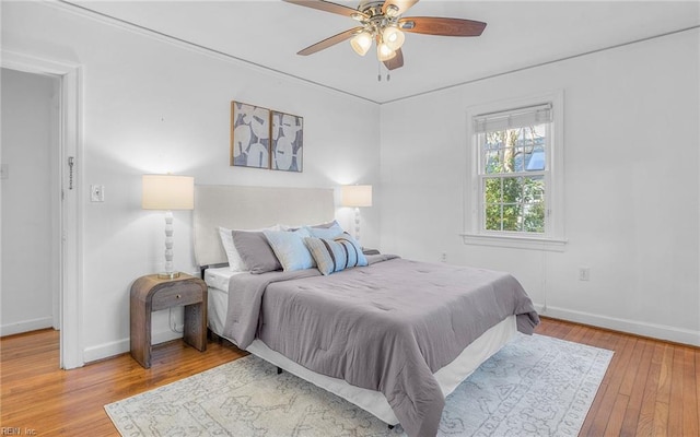 bedroom with a ceiling fan, baseboards, and wood-type flooring