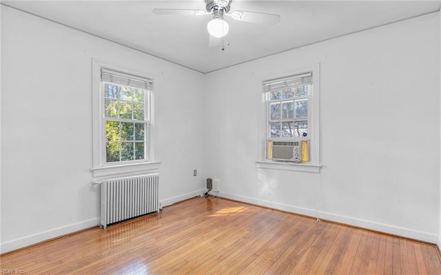 spare room with a wealth of natural light, radiator, light wood-type flooring, and baseboards