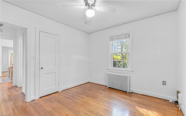 unfurnished room with ceiling fan, baseboards, radiator, and light wood-style flooring