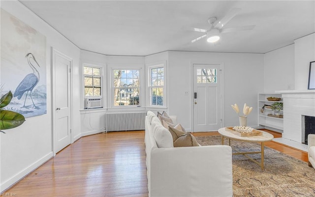 living area featuring a fireplace, radiator heating unit, wood finished floors, and cooling unit