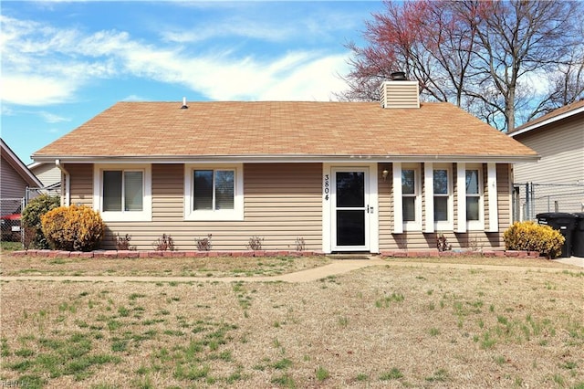 ranch-style home with a chimney and a front yard