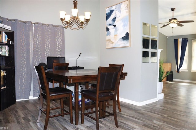 dining area with ceiling fan with notable chandelier, lofted ceiling, wood finished floors, and baseboards