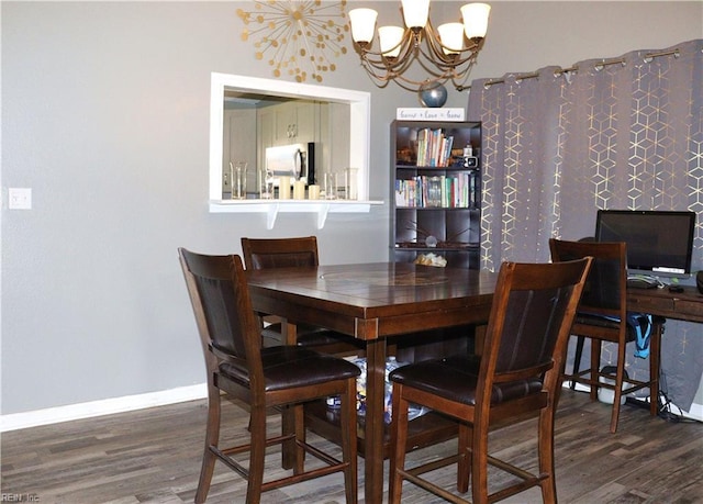 dining space with baseboards, an inviting chandelier, and wood finished floors