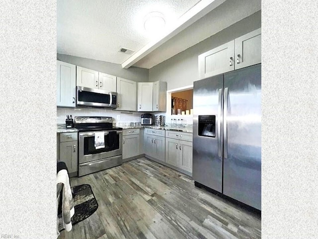 kitchen with tasteful backsplash, light countertops, stainless steel appliances, dark wood-style floors, and a textured ceiling