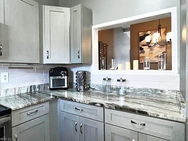 kitchen featuring light stone counters, a chandelier, and backsplash