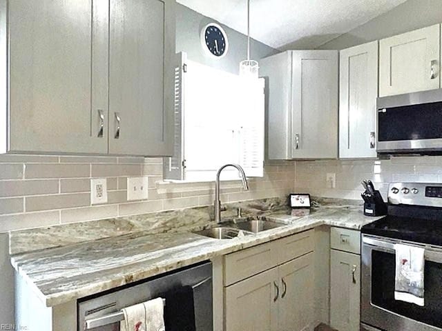 kitchen featuring a sink, tasteful backsplash, white cabinetry, stainless steel appliances, and light stone countertops