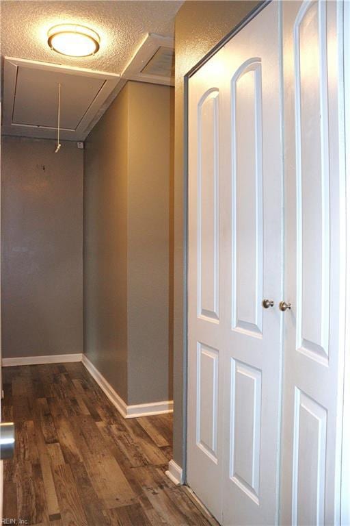 corridor featuring dark wood-style floors, visible vents, attic access, and baseboards