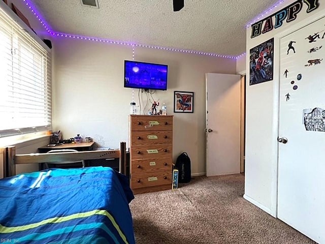 carpeted bedroom featuring a textured ceiling and a ceiling fan