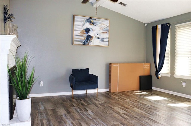 sitting room with visible vents, baseboards, wood finished floors, and vaulted ceiling with beams