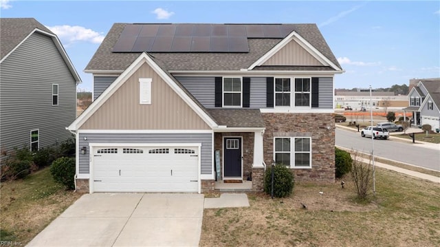 craftsman house featuring stone siding, roof mounted solar panels, roof with shingles, and driveway