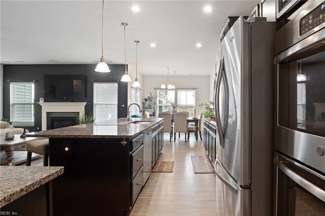 kitchen featuring open floor plan, recessed lighting, appliances with stainless steel finishes, light wood-style flooring, and a sink