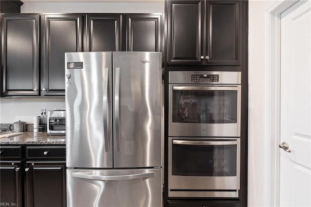 kitchen with dark stone countertops, dark cabinets, and stainless steel appliances