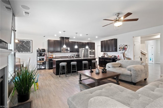 living area with visible vents, recessed lighting, a fireplace, light wood-style floors, and a ceiling fan