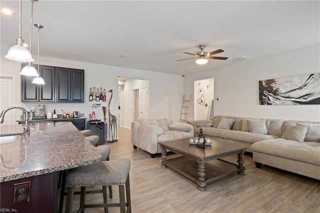 living area featuring light wood-style flooring and a ceiling fan