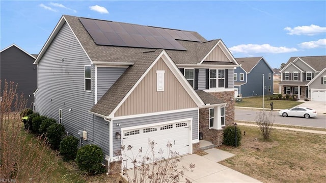 view of front facade featuring solar panels, concrete driveway, a garage, and a shingled roof