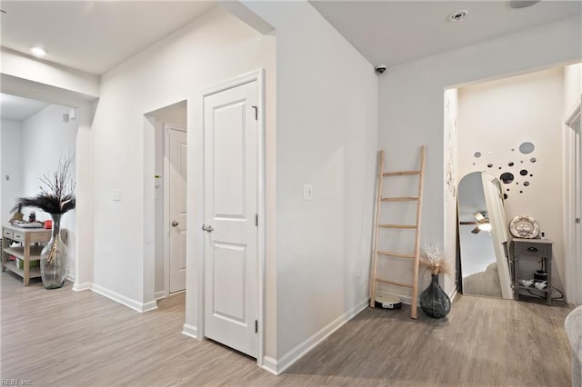 corridor featuring baseboards and light wood finished floors