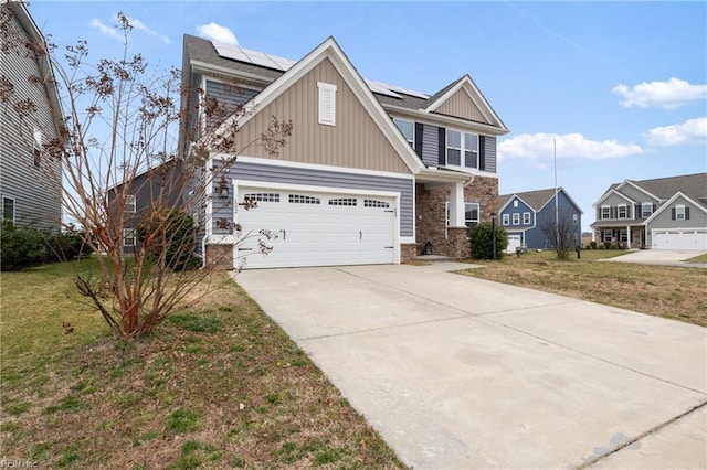 view of front facade with a front yard, solar panels, concrete driveway, stone siding, and board and batten siding